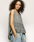 Woman wearing a sleeveless, layered top with a neutral background