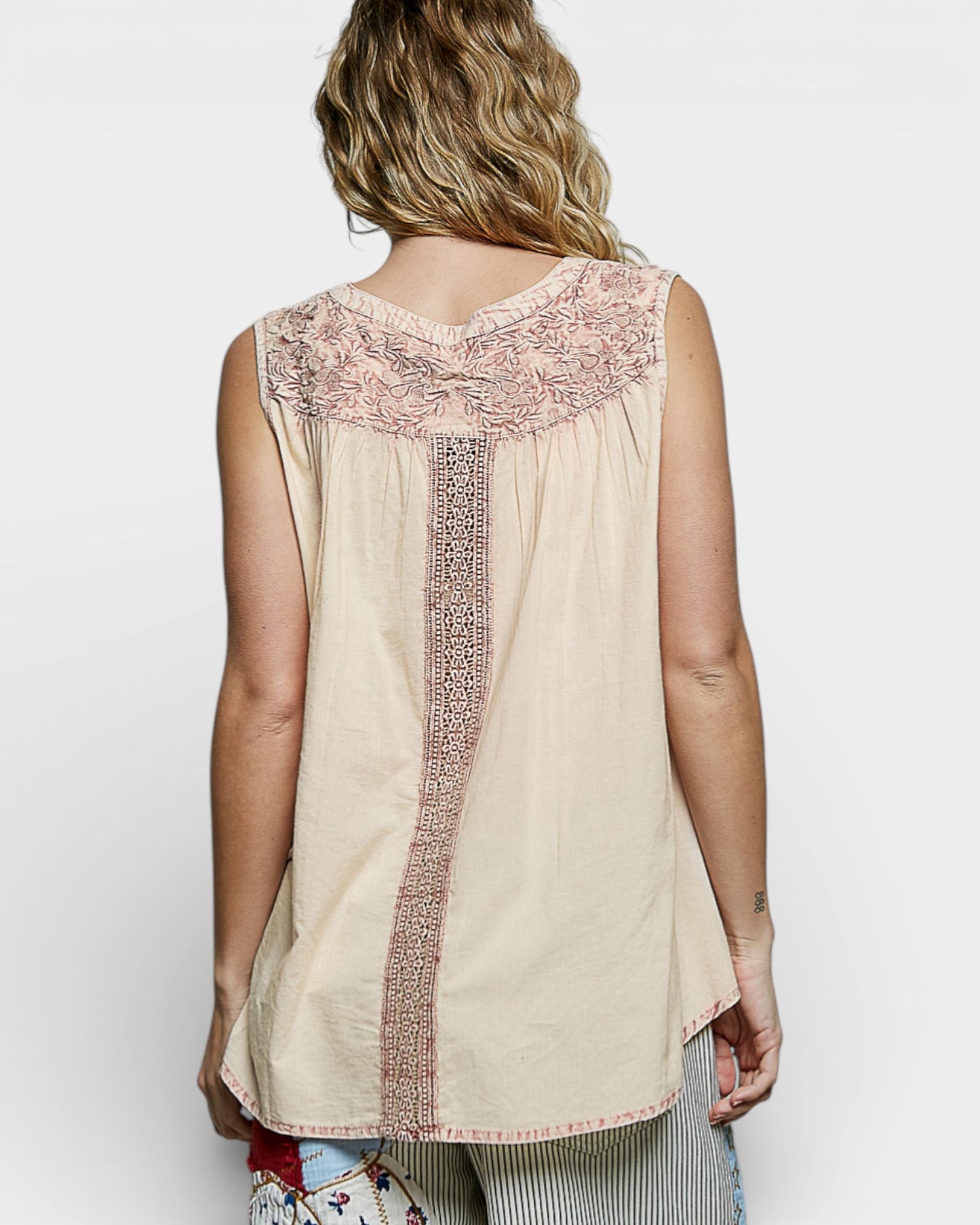 Beige sleeveless top with intricate embroidery on a plain background