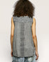 Person wearing a sleeveless patterned top against a plain background