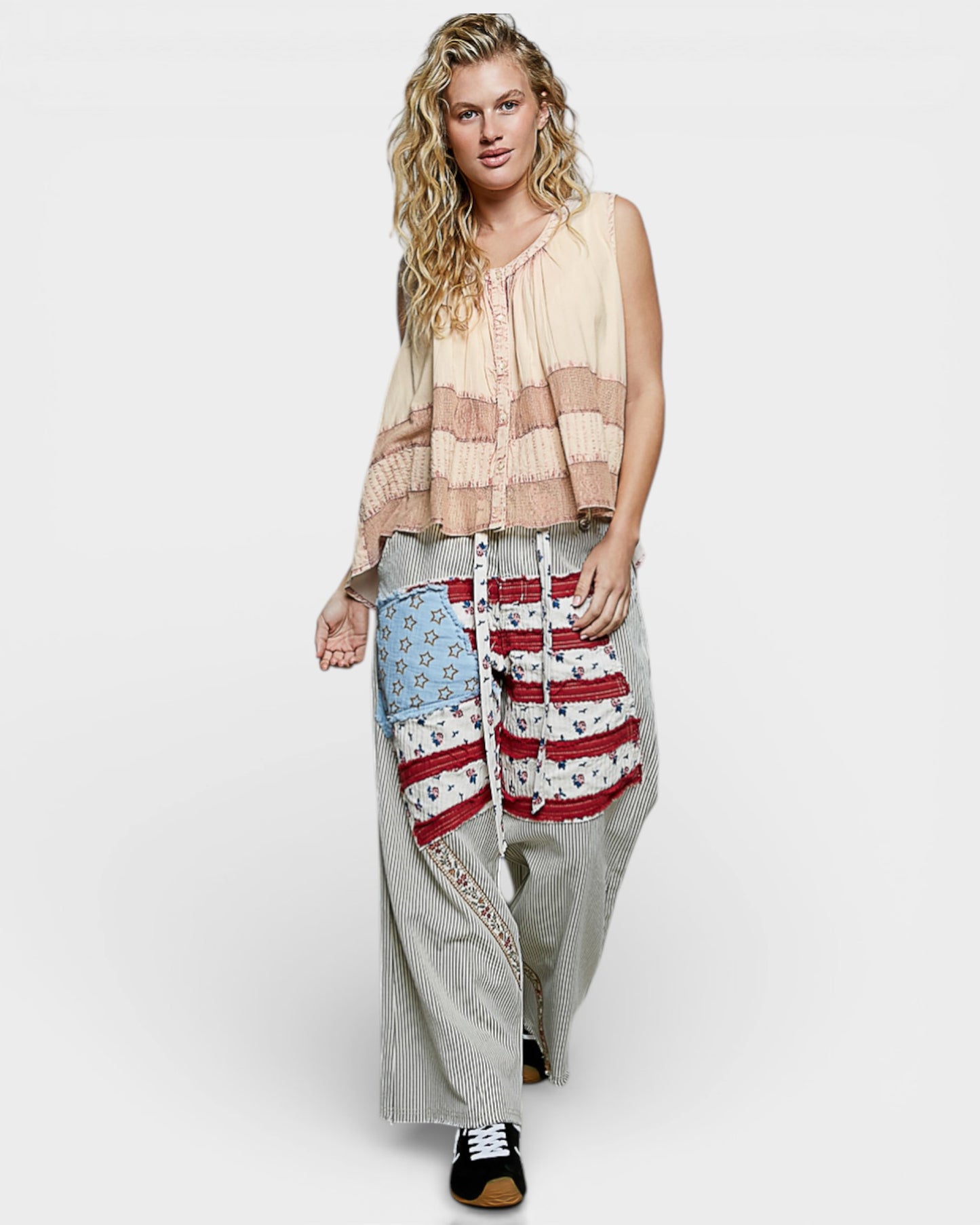 Woman wearing a sleeveless top and patterned pants on a white background