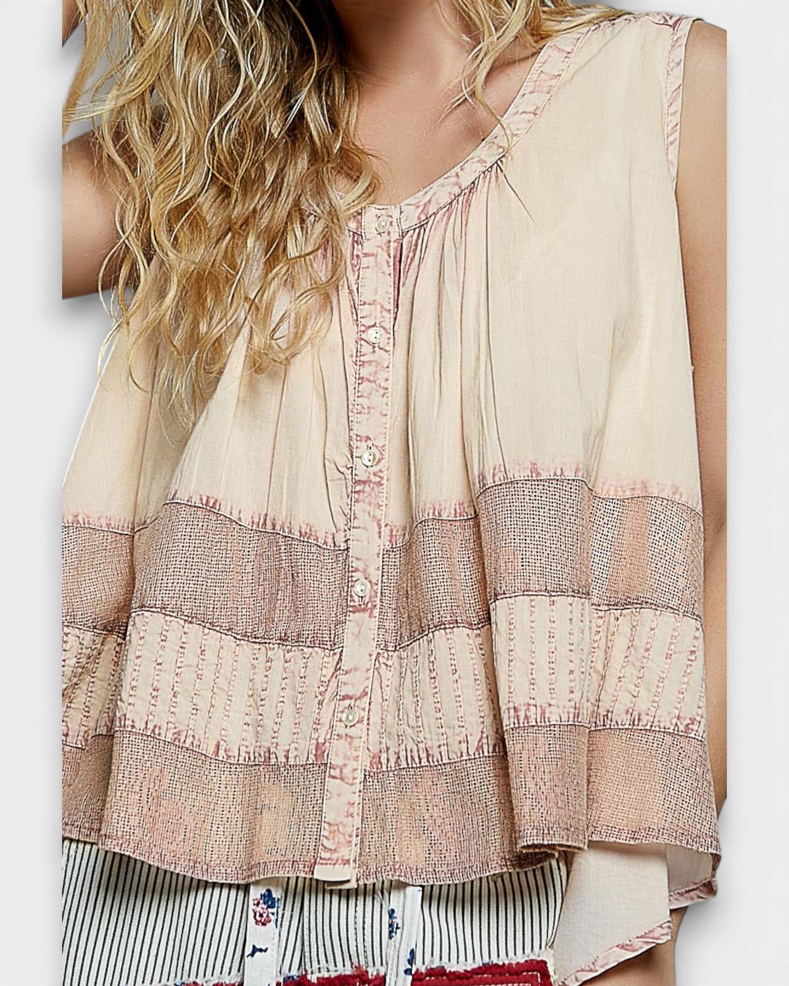 Woman wearing a sleeveless top with intricate patterns on a white background