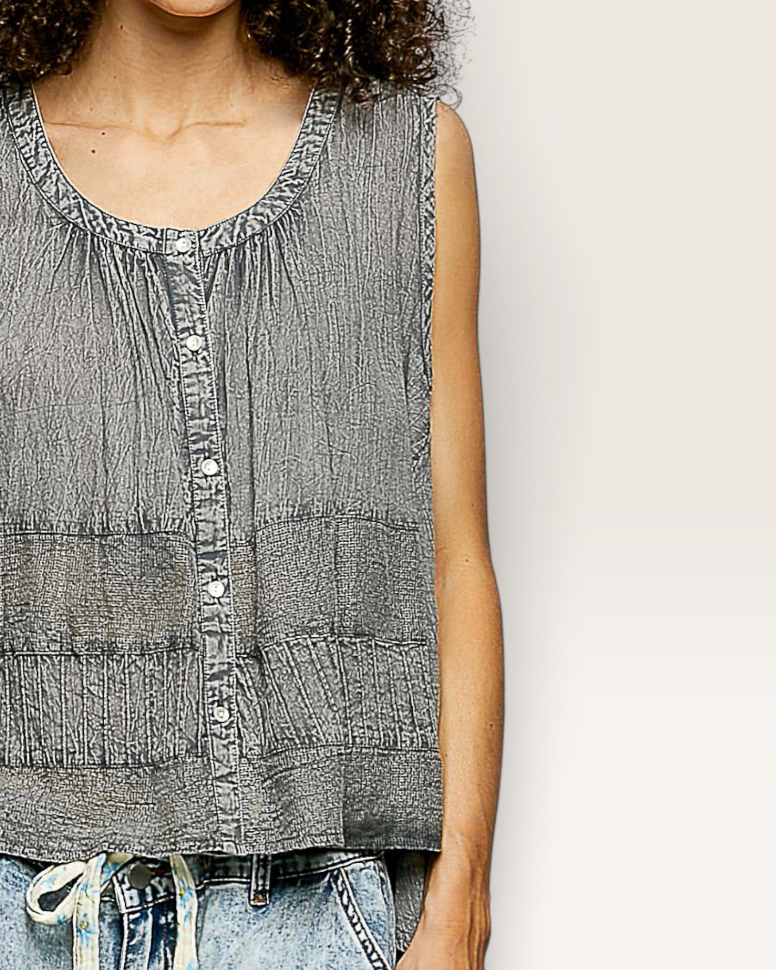 Woman wearing a sleeveless denim top against a plain background