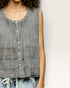 Woman wearing a sleeveless denim top against a plain background