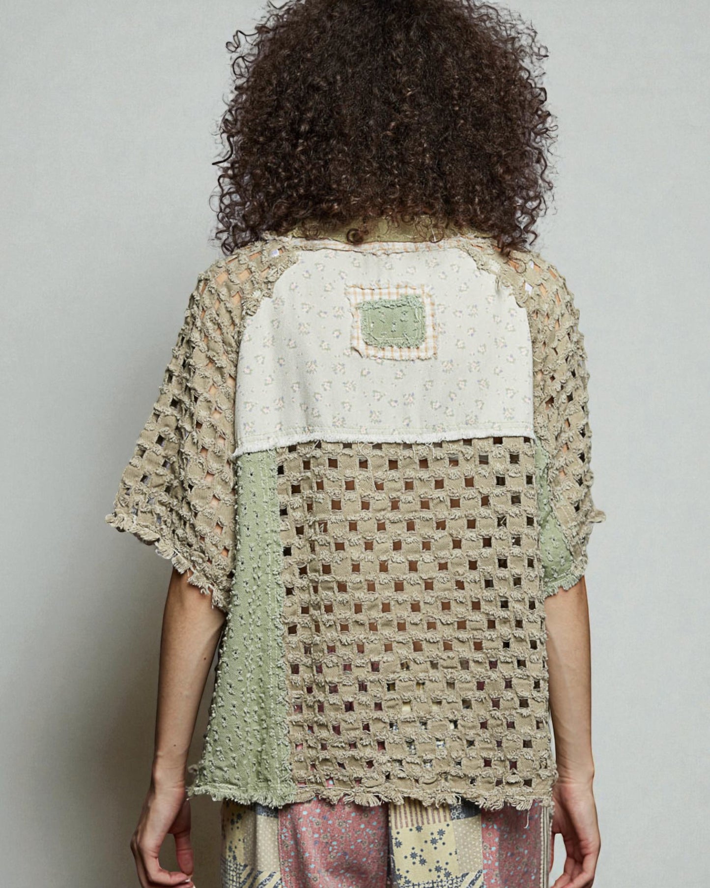 Person wearing a textured, patterned top with a neutral background