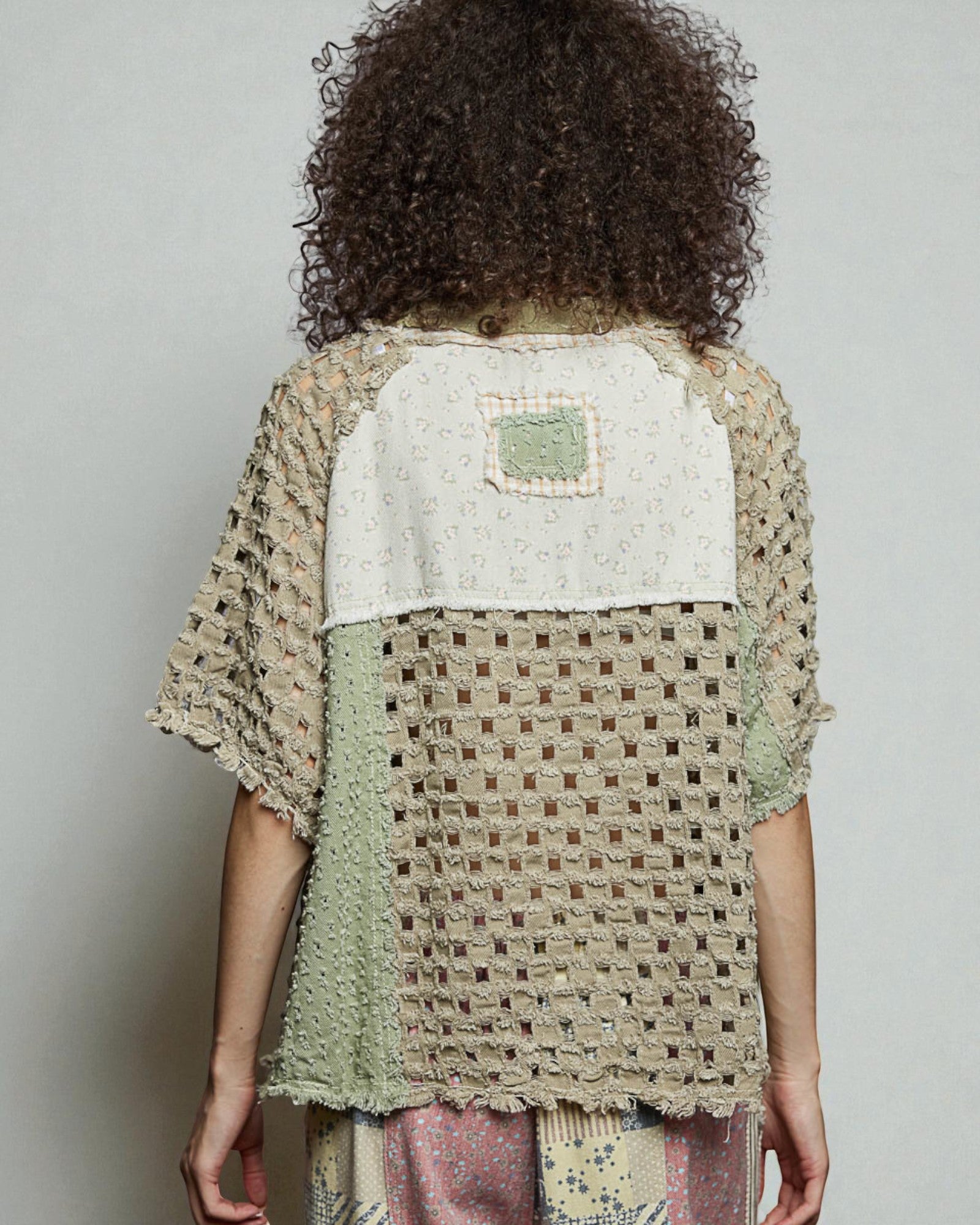 Person wearing a textured, patterned top with a neutral background