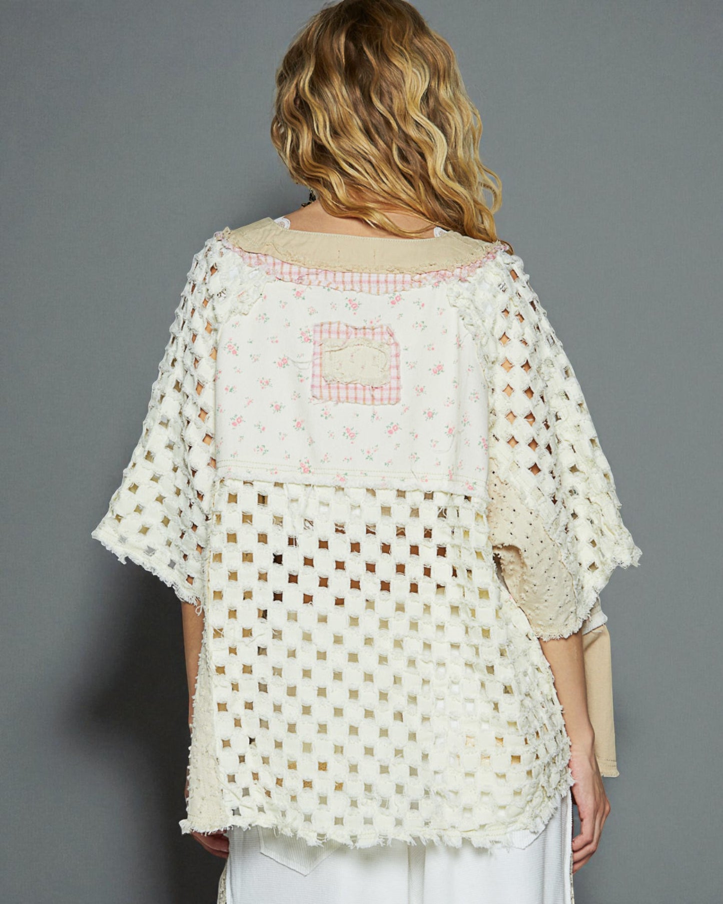 Woman wearing a white crochet top with a gray background