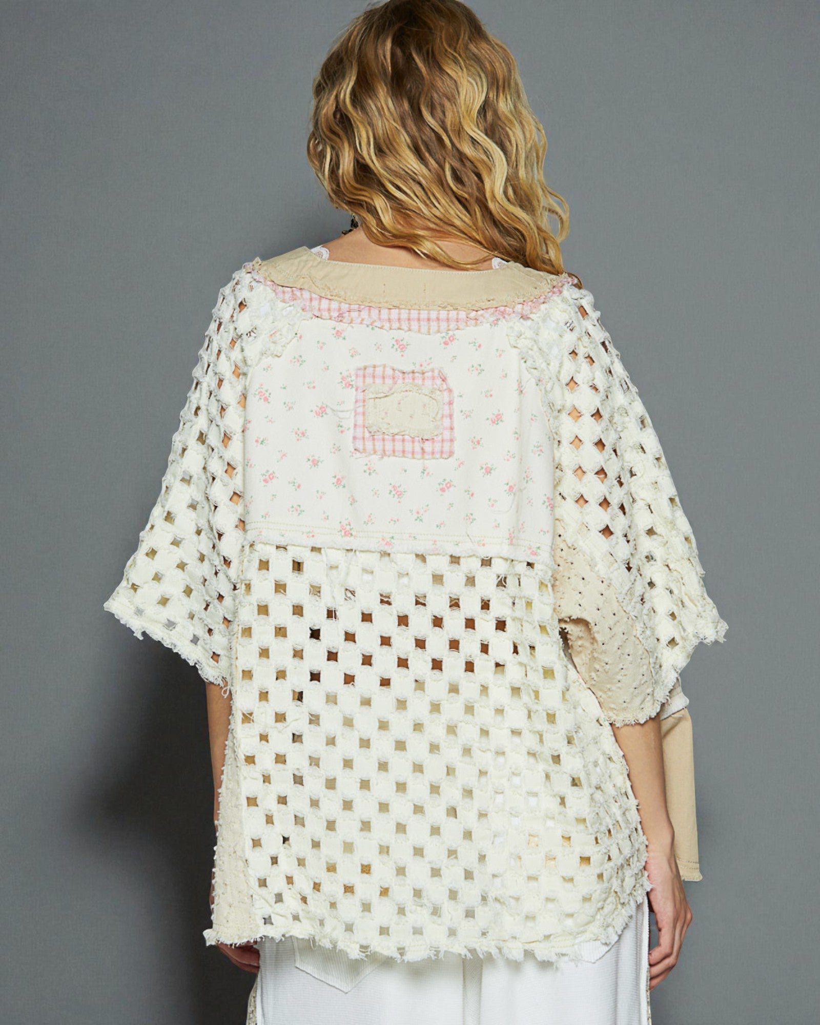 Woman wearing a white crochet top with a gray background