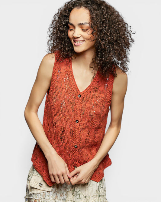 Woman wearing a red knitted vest on a plain background