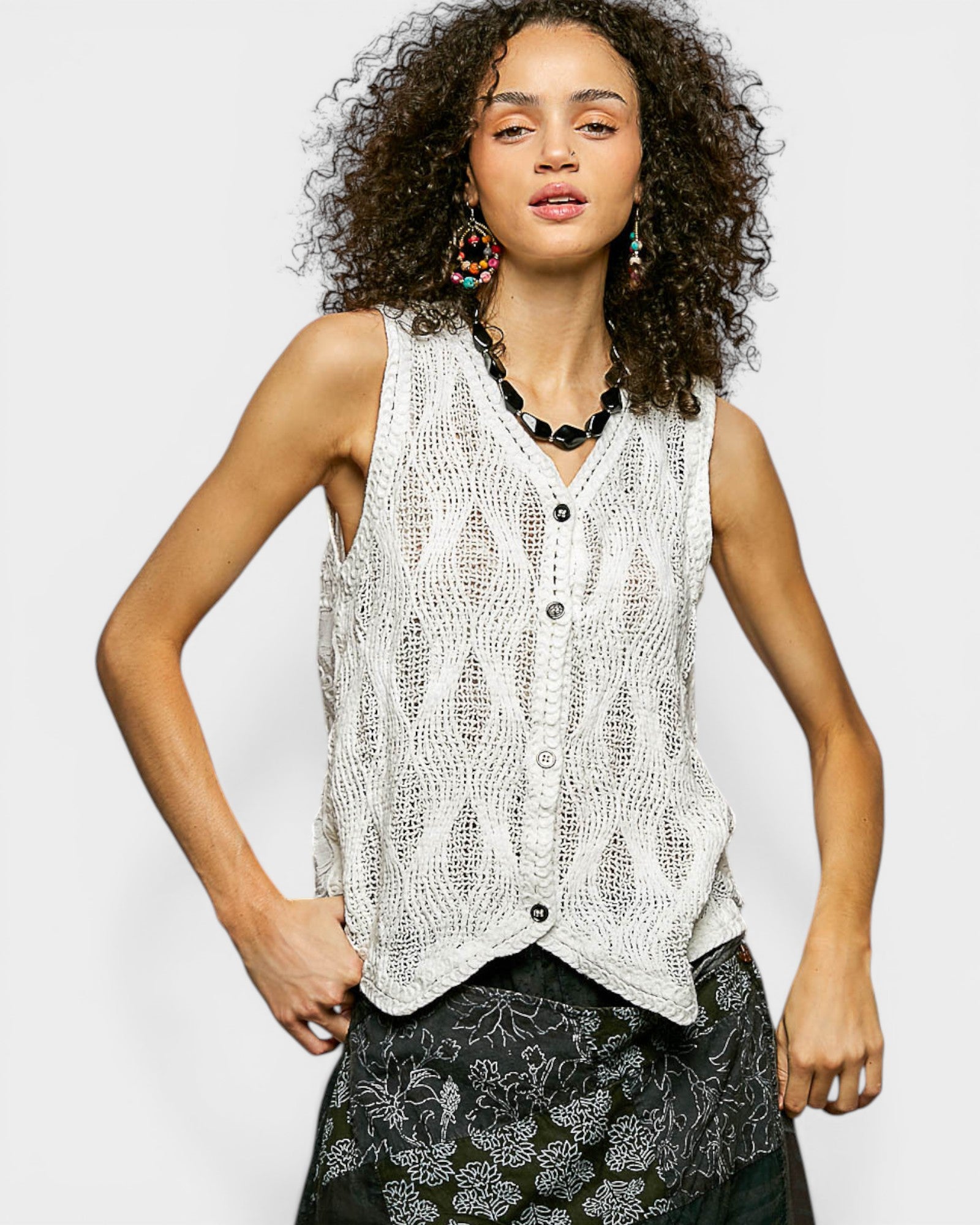 Woman wearing a sleeveless knitted top with a plain background