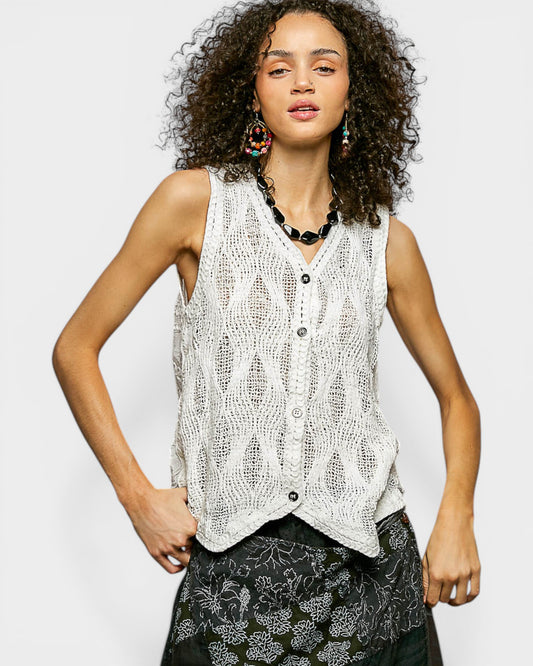 Woman wearing a sleeveless knitted top with a plain background