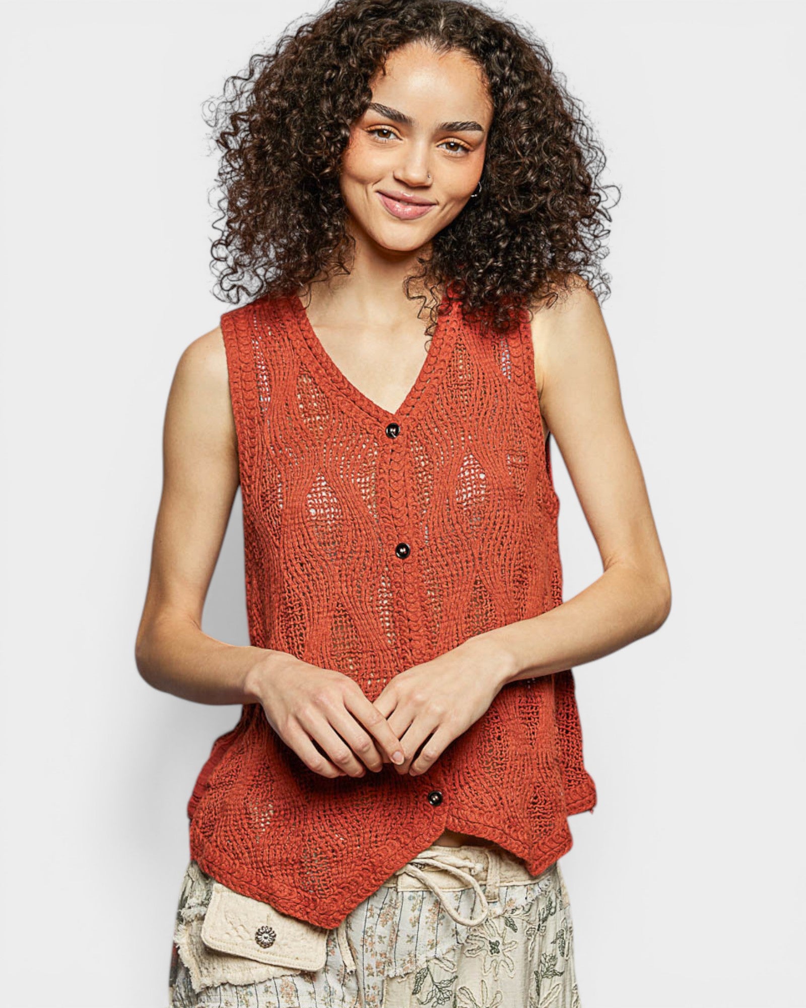 Woman wearing a red sleeveless knitted top against a plain background