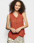 Woman wearing a red sleeveless knitted top against a plain background