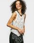 Woman wearing a sleeveless patterned top and black skirt against a white background