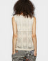 Person wearing a sleeveless lace top with a plain background