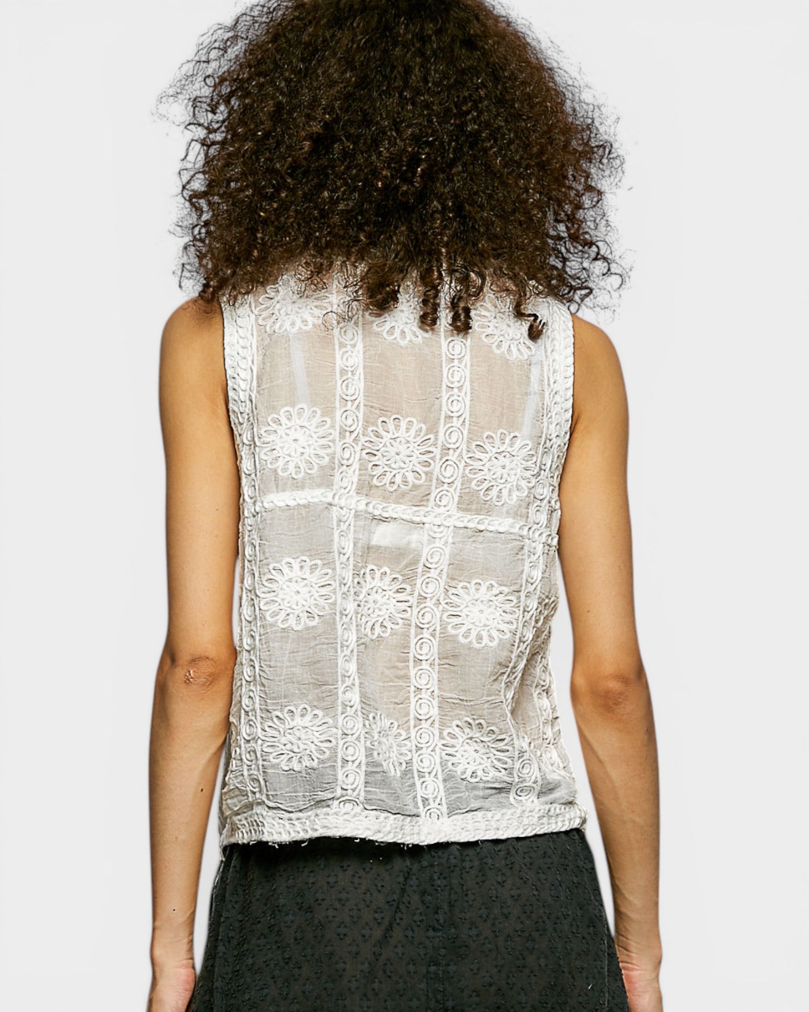Person wearing a sleeveless lace top on a plain background