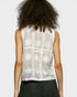 Person wearing a sleeveless lace top on a plain background
