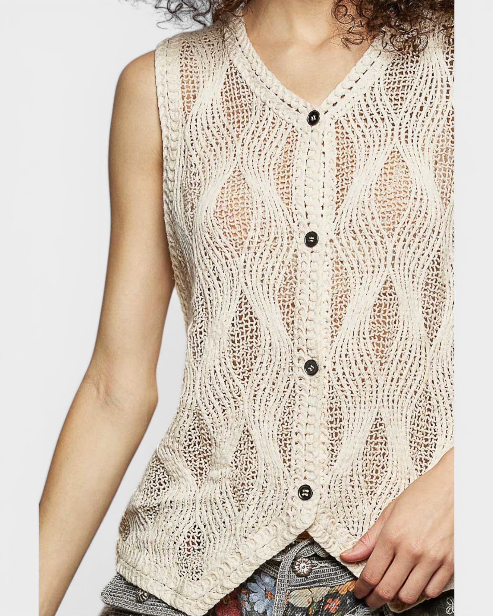 Beige knitted vest worn by a person on a plain background