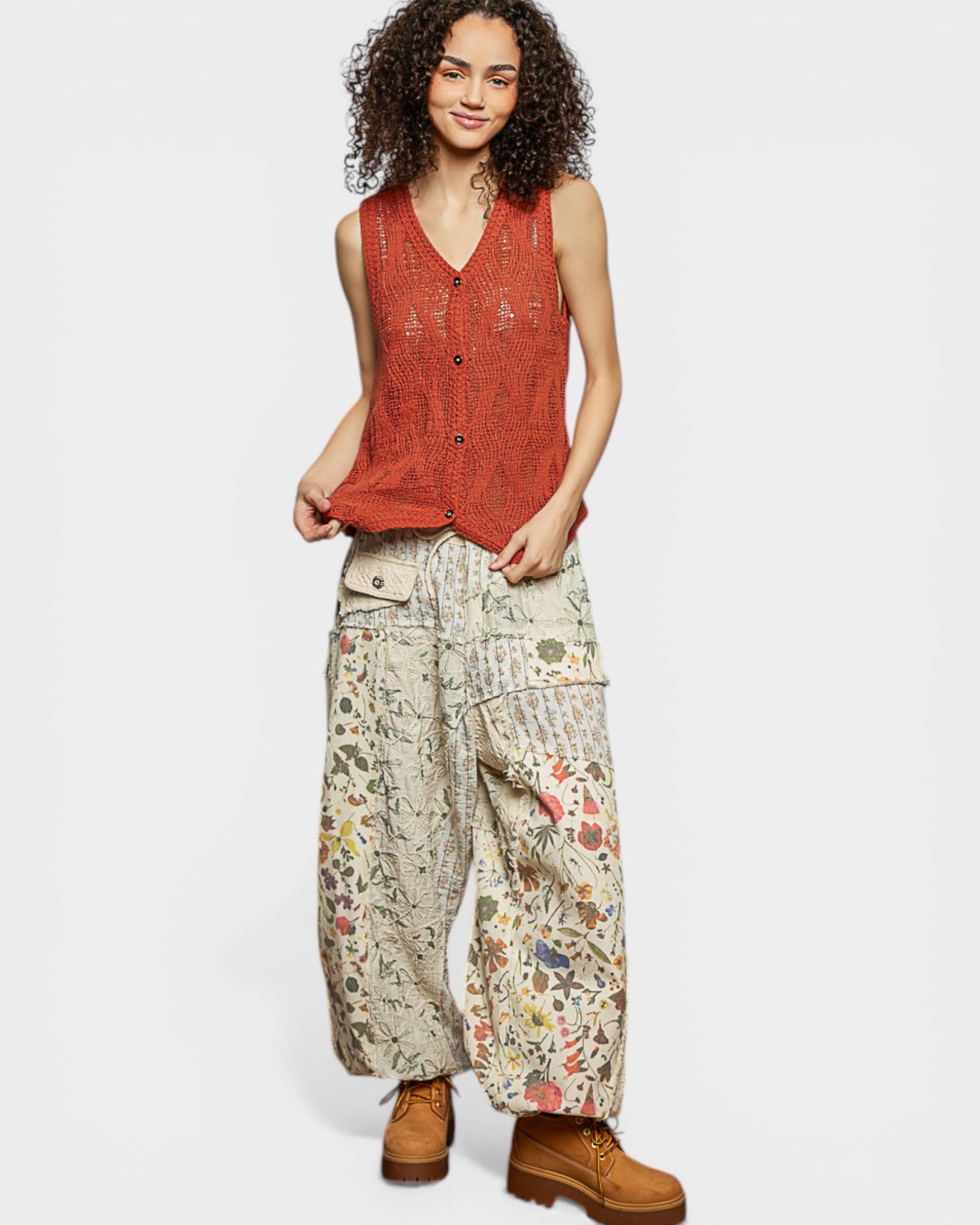 Woman wearing a red sleeveless top and floral pants on a white background