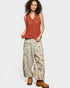 Woman wearing a red sleeveless top and floral pants on a white background