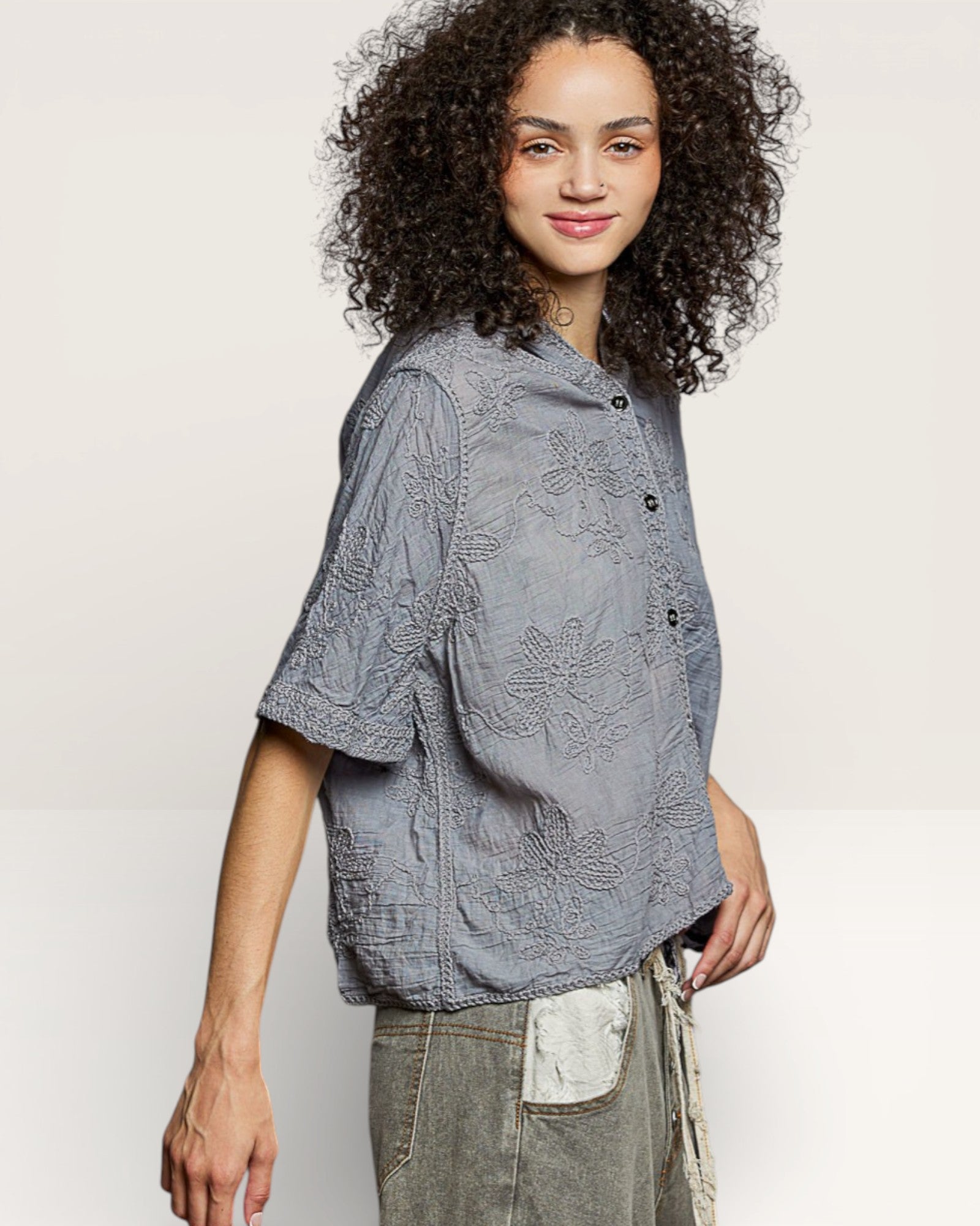 Woman wearing a gray textured blouse against a plain background