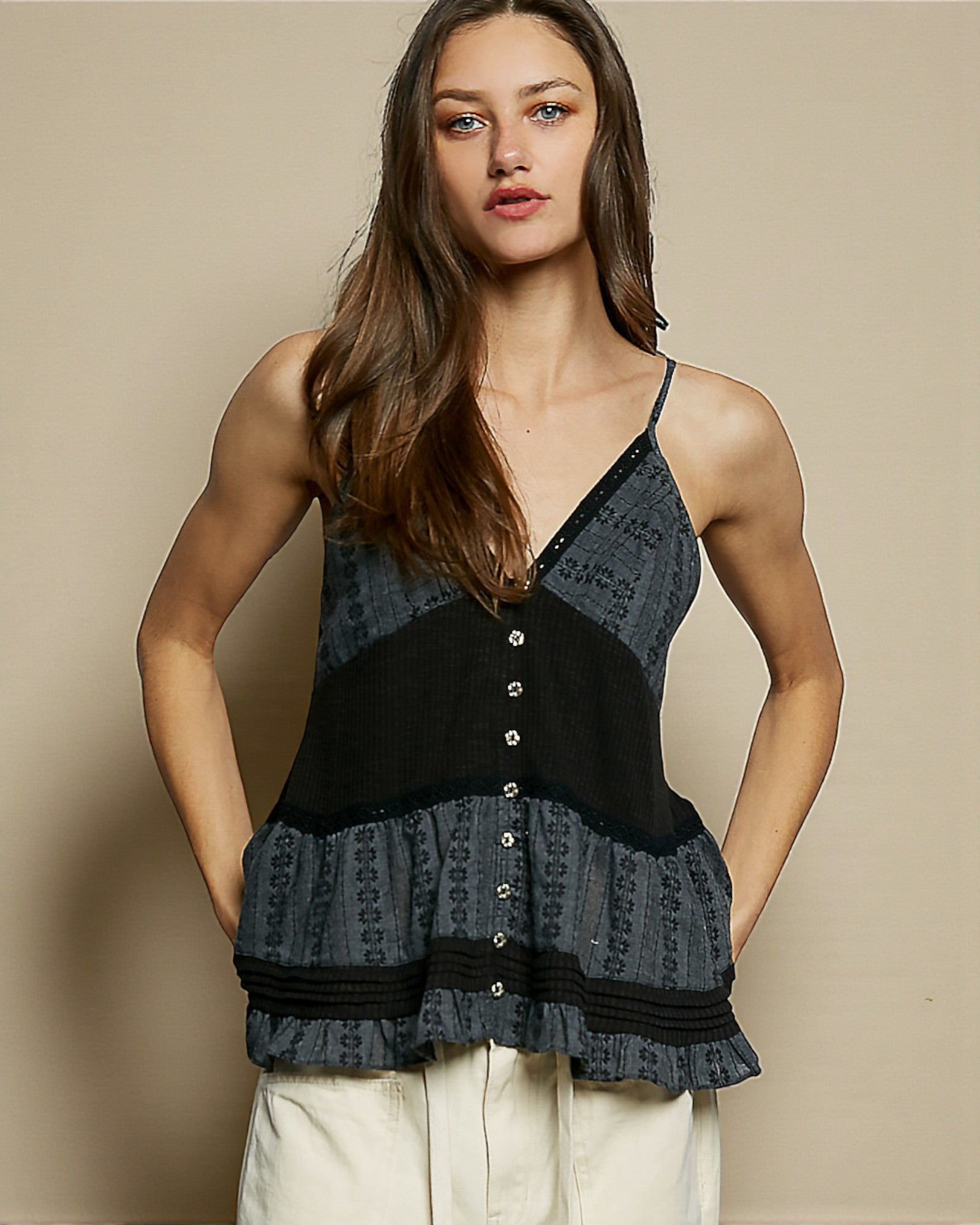 Woman wearing a black and gray patterned top against a beige background