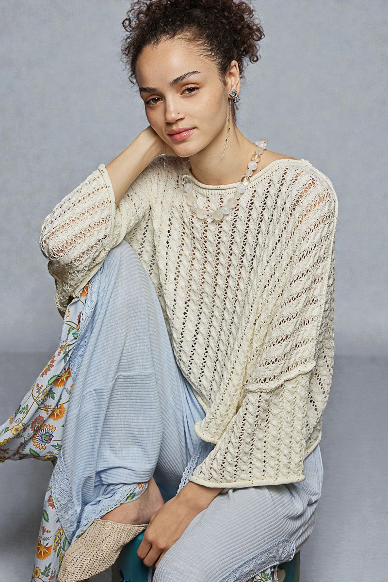 Woman wearing a textured beige sweater with a gray background