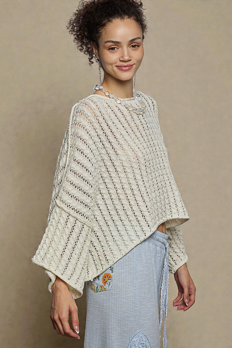 Woman wearing a cream-colored knitted poncho against a beige background