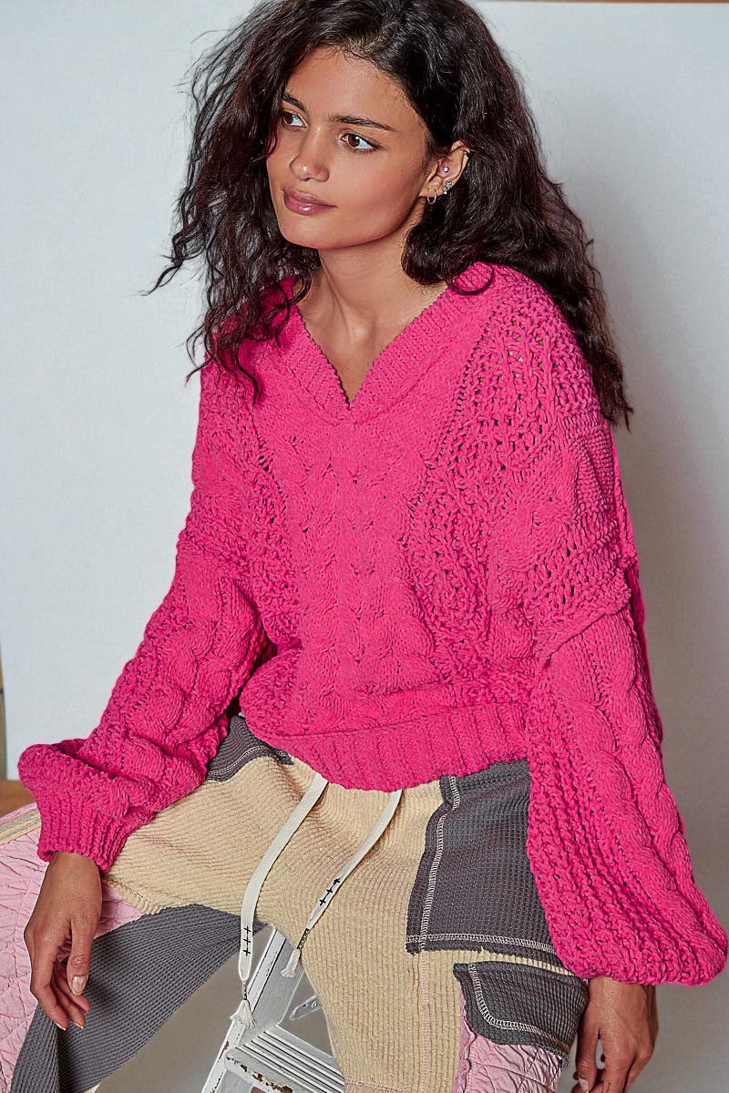 Woman wearing a bright pink knitted sweater against a plain background
