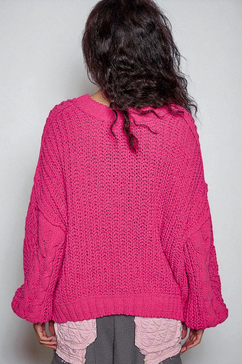 Person wearing a pink knitted sweater against a plain background