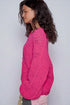 Woman wearing a bright pink crochet sweater against a plain background
