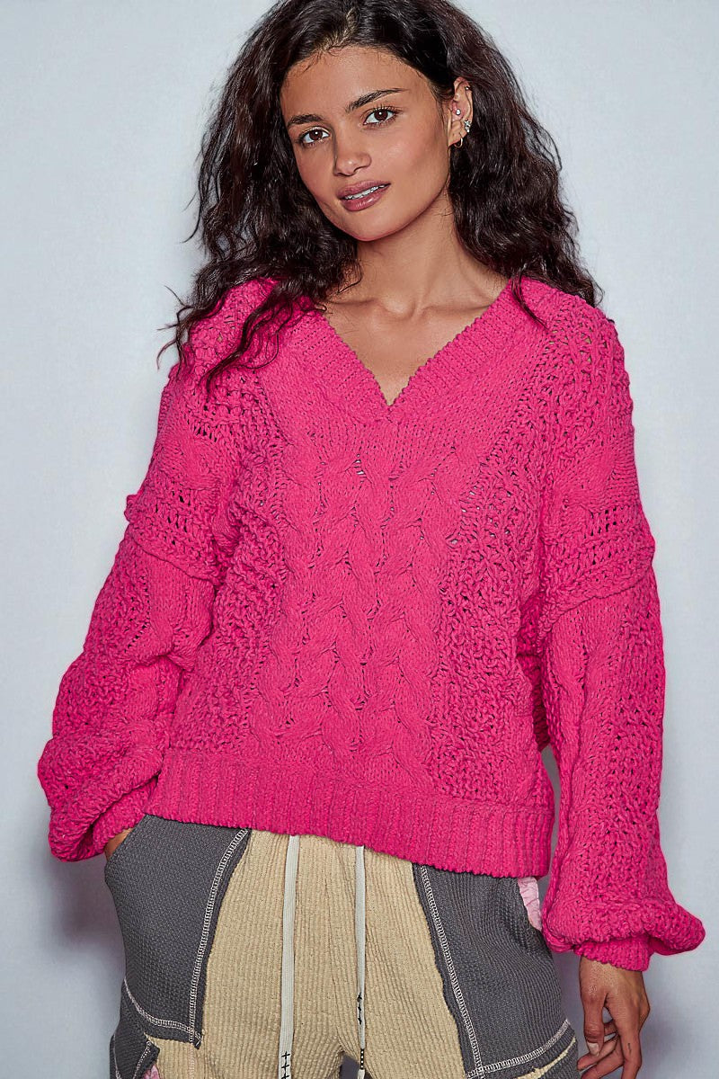 Woman wearing a bright pink knitted sweater against a plain background