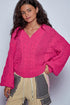 Woman wearing a bright pink knitted sweater against a plain background