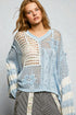 Woman wearing a light blue crochet top with a gray background