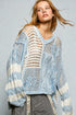 Woman wearing a light blue and white patterned sweater against a gray background