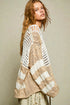 Woman wearing a beige and white crochet cardigan against a plain background