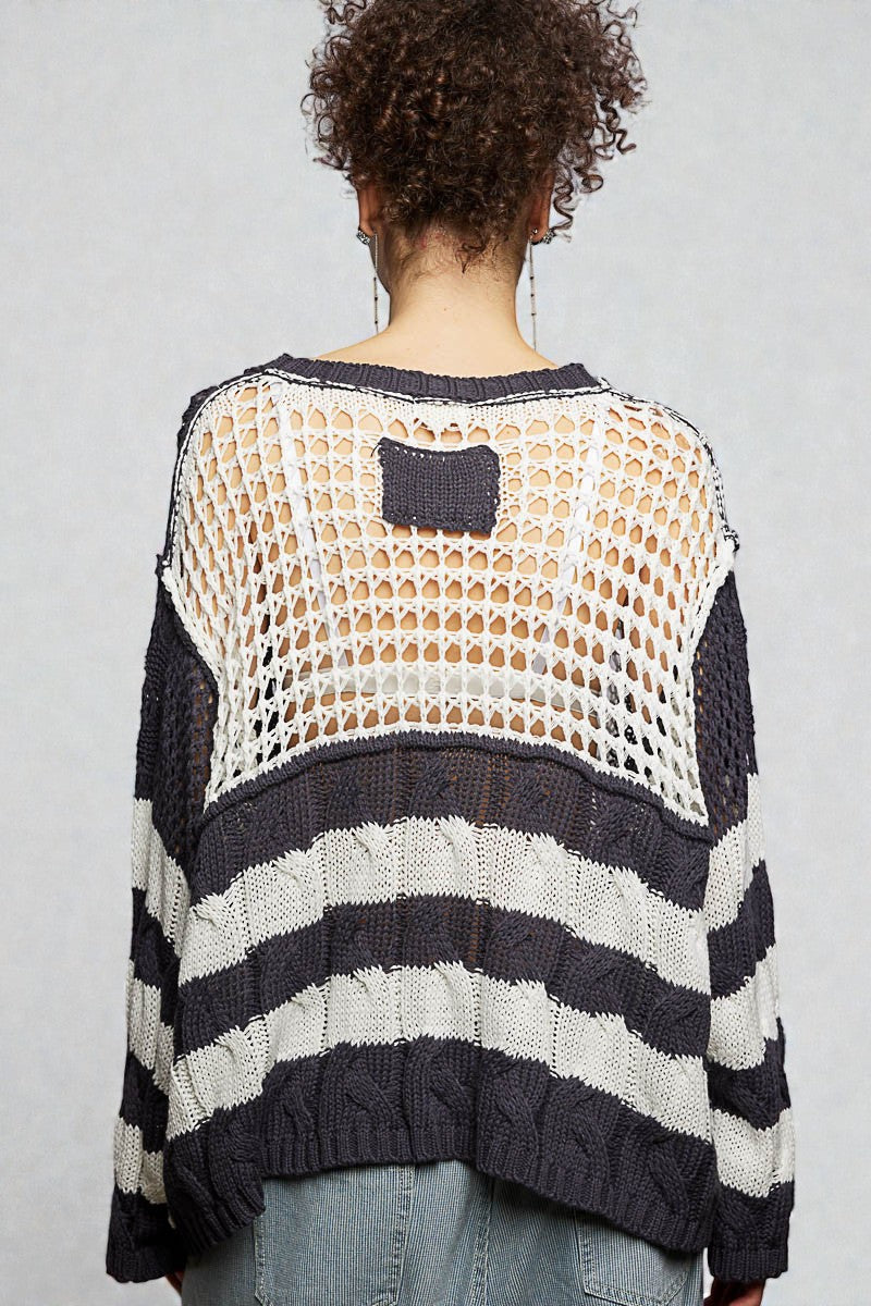 Person wearing a black and white striped sweater with a mesh back panel on a plain background