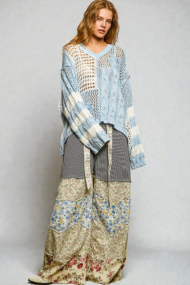 Woman wearing a patterned outfit with a blue cardigan against a plain background