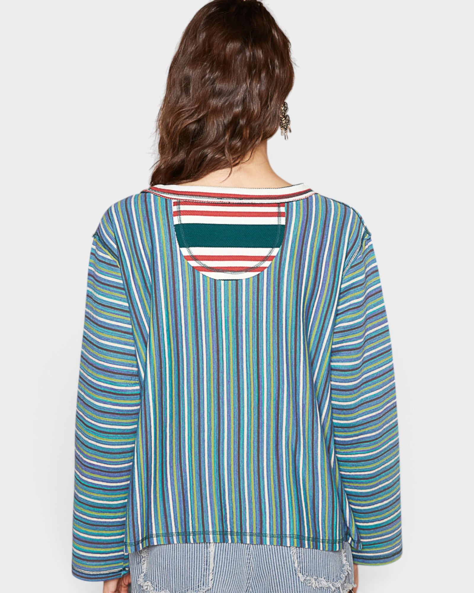 Woman wearing a colorful striped shirt with a plain background