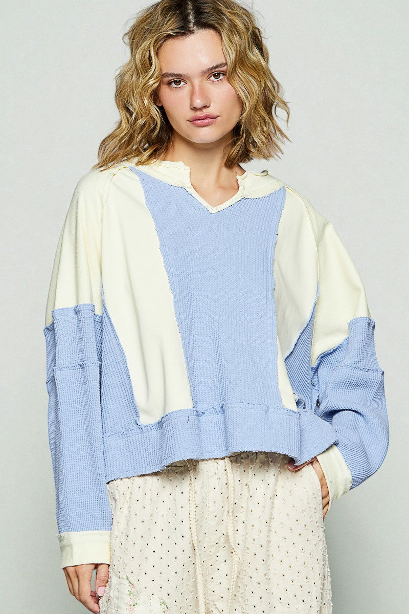 Woman wearing a color-blocked sweater with blue and beige tones on a plain background