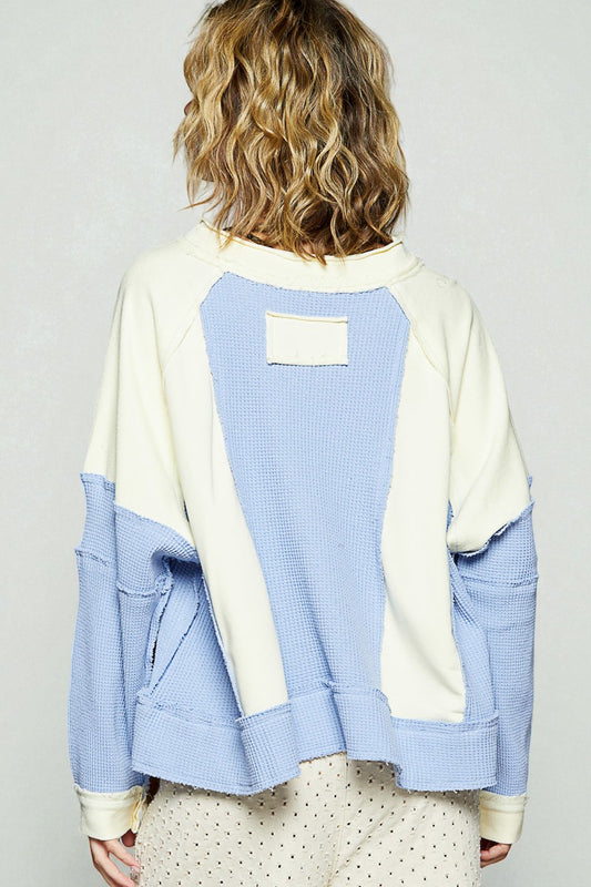 Person wearing a blue and beige jacket with a plain background