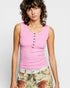 Woman wearing a pink sleeveless top with colorful buttons on a white background