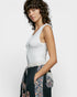 Woman wearing a white sleeveless top and floral skirt on a plain background