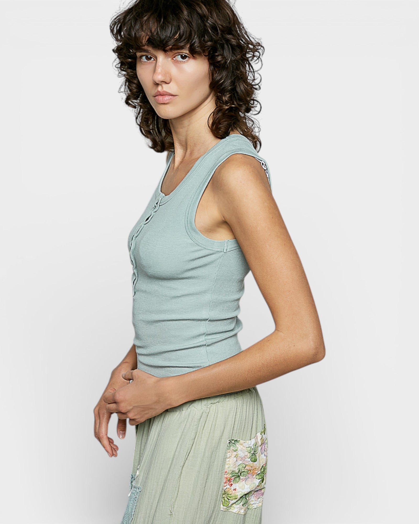 Woman wearing a light blue sleeveless top with a plain background