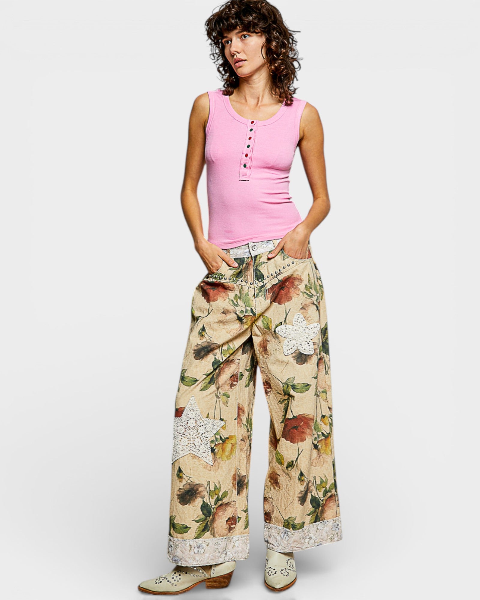 Woman wearing a pink sleeveless top and floral pants on a white background