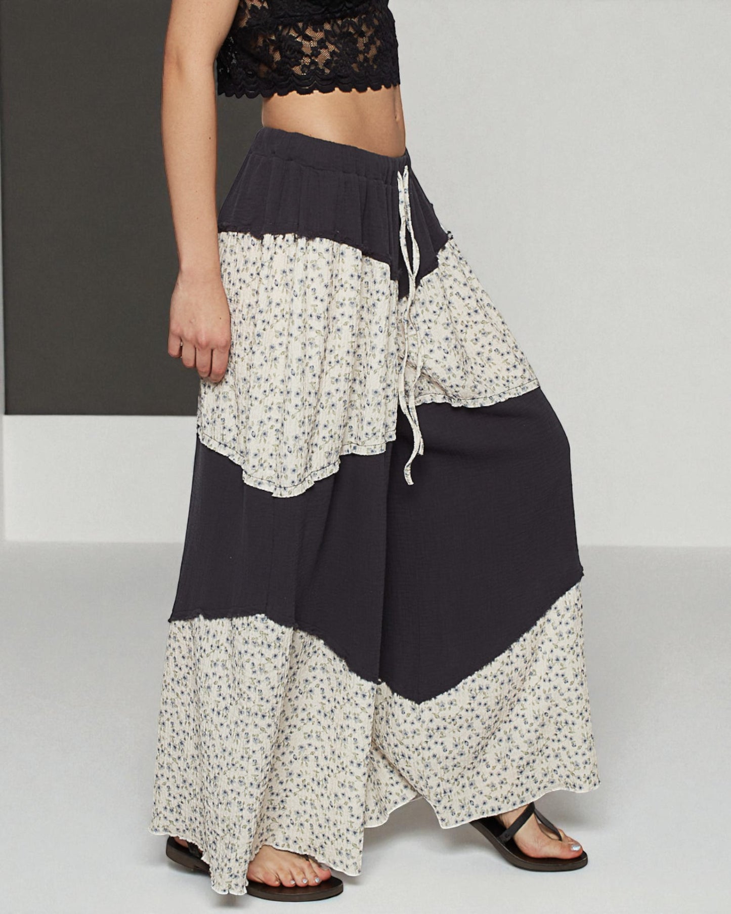 Person wearing a black and white floral layered skirt on a plain background