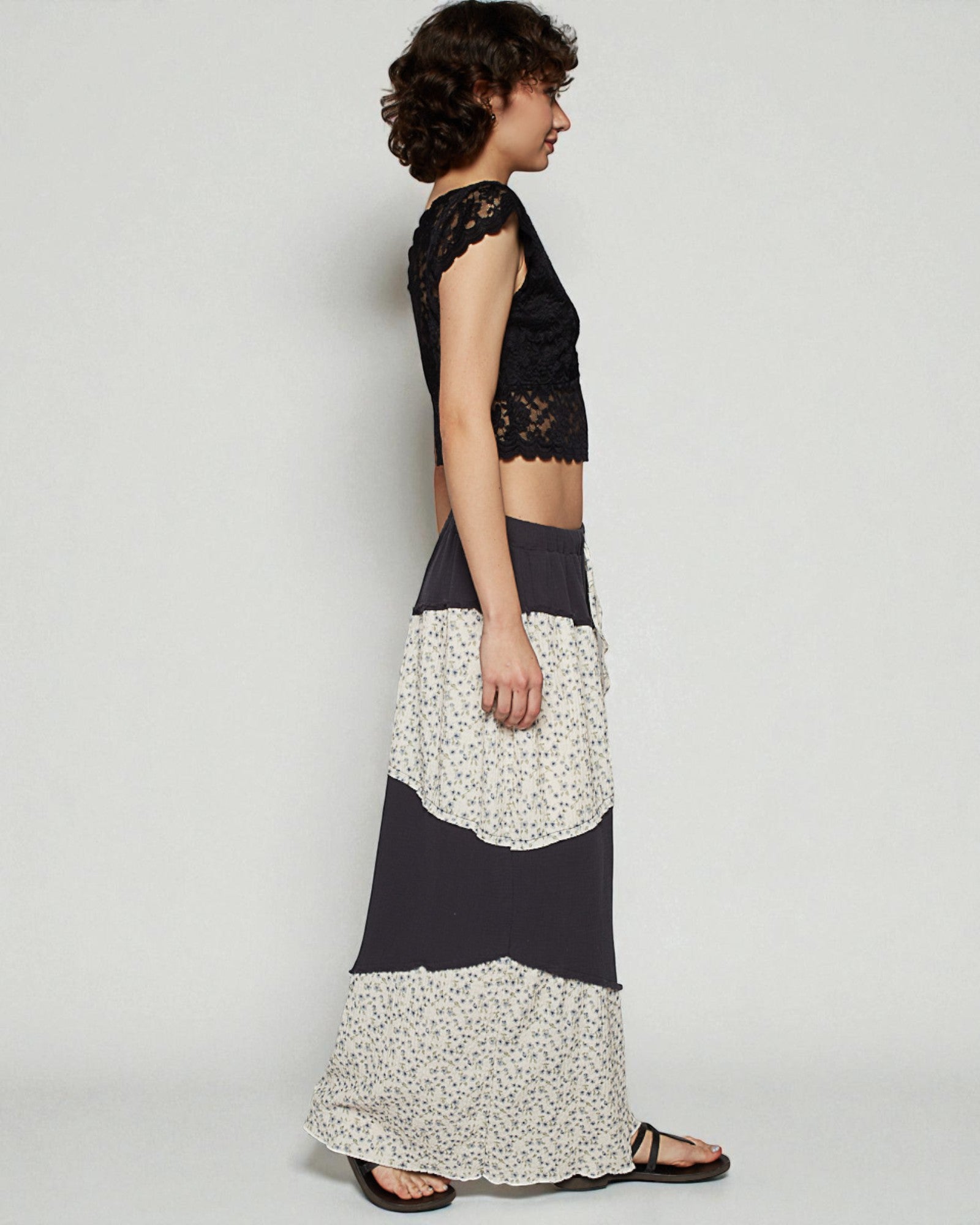 Woman wearing a black lace top and a long floral skirt on a white background