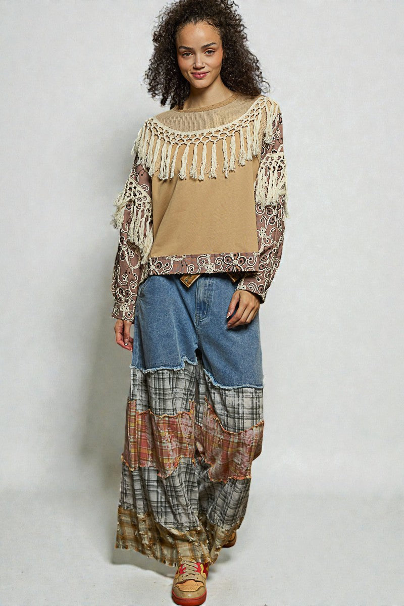 Woman wearing a patterned top and plaid skirt with denim pants on a plain background