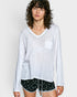 Woman wearing a white long-sleeve top with a pocket and black shorts with white patterns on a plain background
