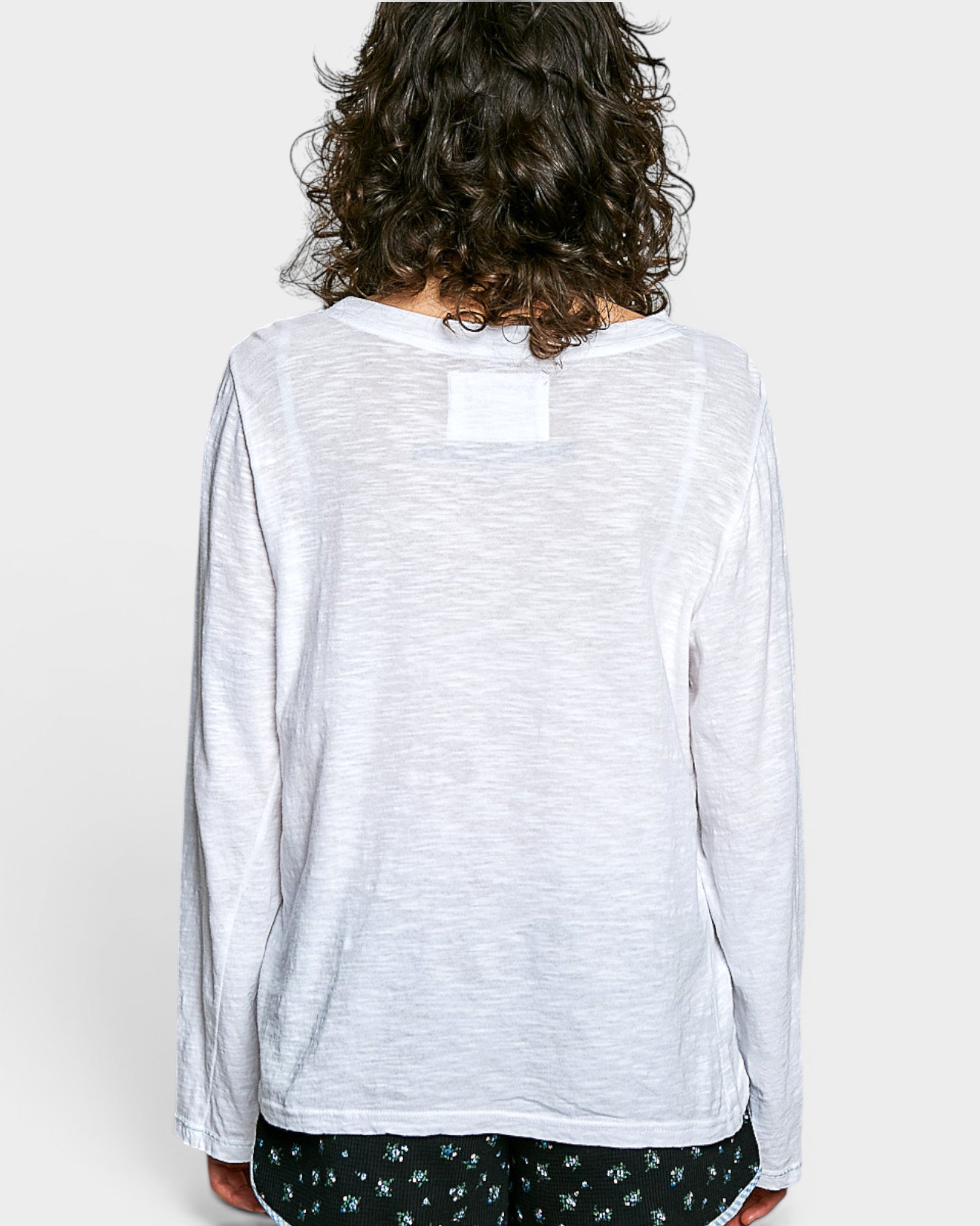 Person wearing a white long-sleeve shirt with a subtle pattern on a plain background