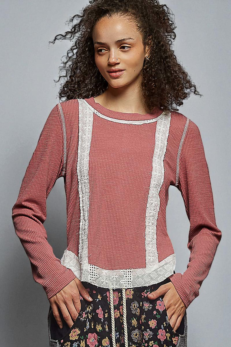Woman wearing a pink sweater with lace details on a gray background